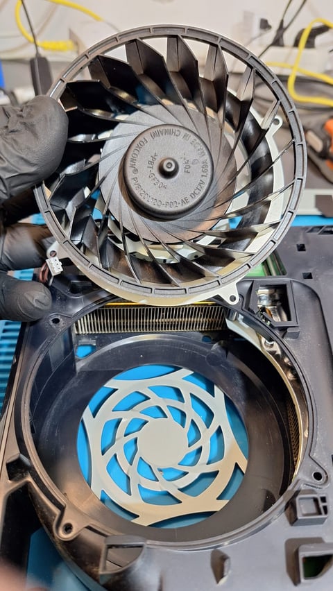 Disassembled computer cooling fans showing metal blade designs and circular vents from internal components
