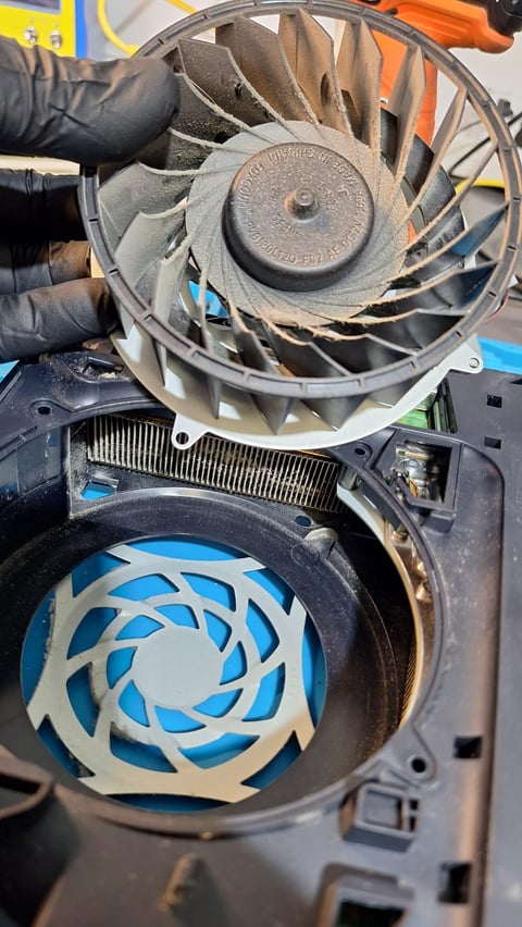 Person holding disassembled laptop cooling fans showing internal metal blades and plastic blue fan components